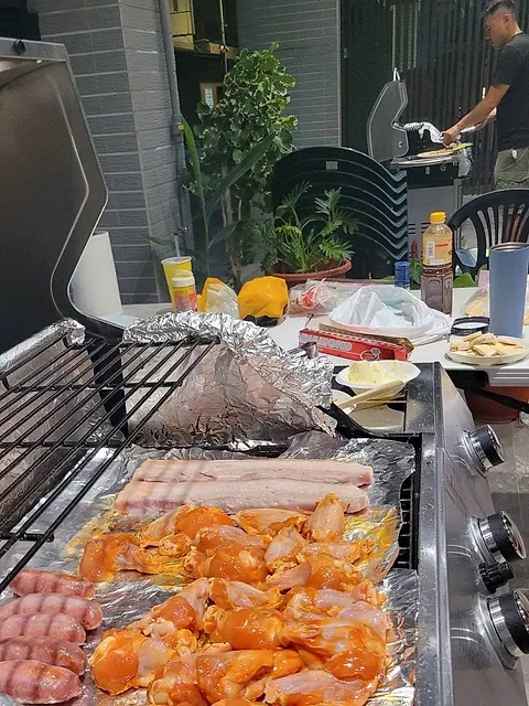 烤網上鋪滿醃製雞腿、香腸與五花肉，準備下爐燒烤