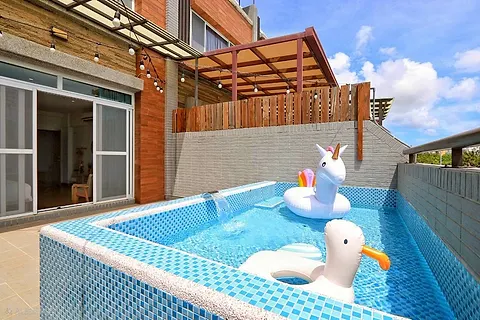 Side view of the second-floor terrace pool with a wood deck and shaded seating area
