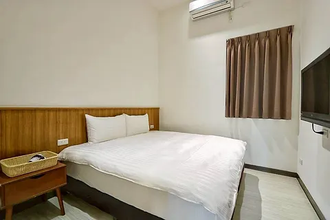 Double bed with wood-paneled headboard, coffee-colored curtains, and wall-mounted TV