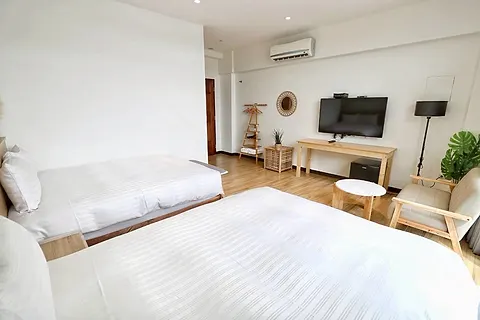 Twin-bed quad room with a round rattan mirror and wood shelving, with its own large terrace and pool