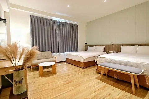 Twin-bed quad room with a sage green accent wall, grey curtains, and cream sofa