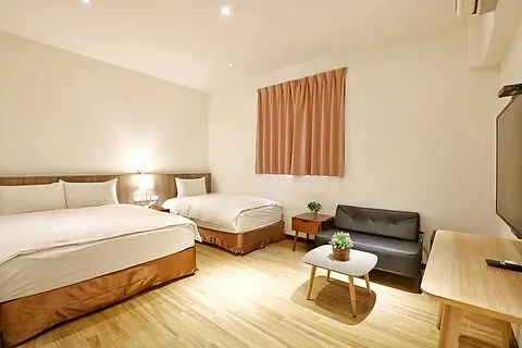 Twin-bed triple room with coral curtains and a black leather sofa