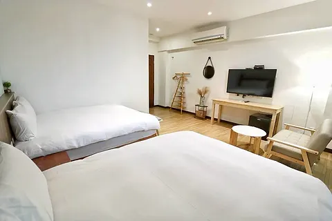 Twin-bed quad room with a round hanging mirror and wood clothes rack, with its own large terrace and pool