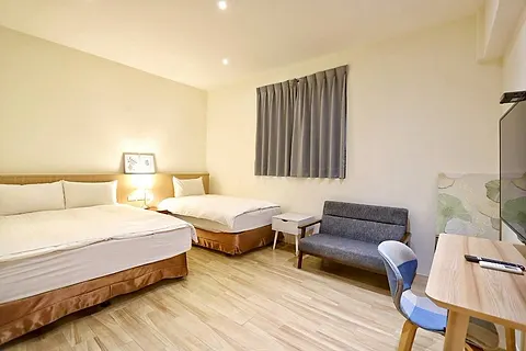 Twin-bed triple room with grey curtains and a blue-grey sofa