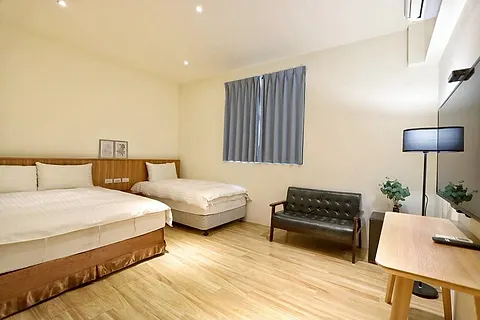 Twin-bed triple room with a wood headboard and dark leather sofa