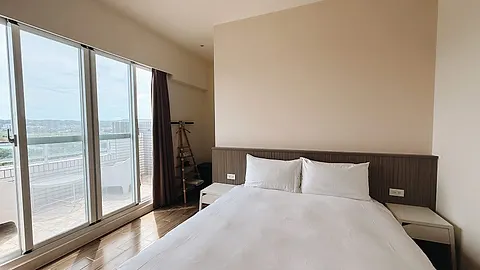 Double room with white bedding, a wood headboard wall, and floor-to-ceiling windows opening onto a private rooftop terrace