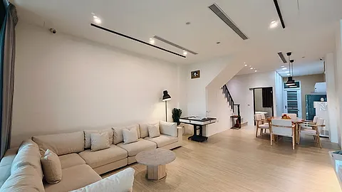 Nikoniko Gathering Hall’s living and dining area, a cream sofa alongside a wooden dining table under vintage pendant lamps