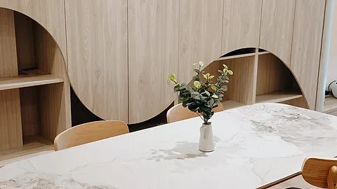 客廳木質收納櫃設計特寫，拱形鏤空搭配大理石餐桌與尤加利葉裝飾