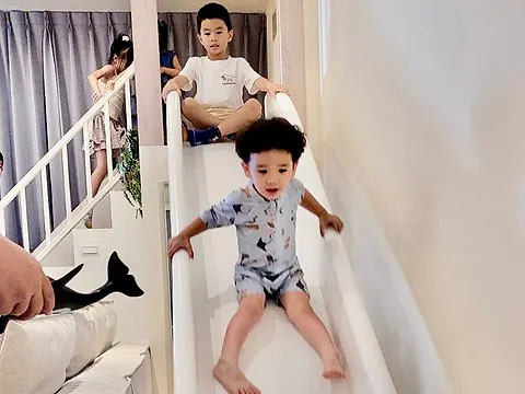 小小孩正從溜滑梯往下滑，後方哥哥坐在滑梯頂端